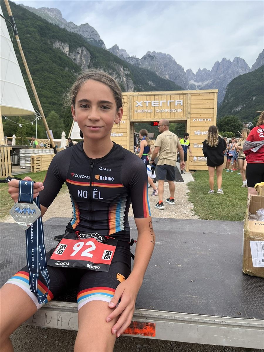 Noël sentado junto al arco de meta del XTERRA European Championship, con la medalla de finisher y el dorsal 92